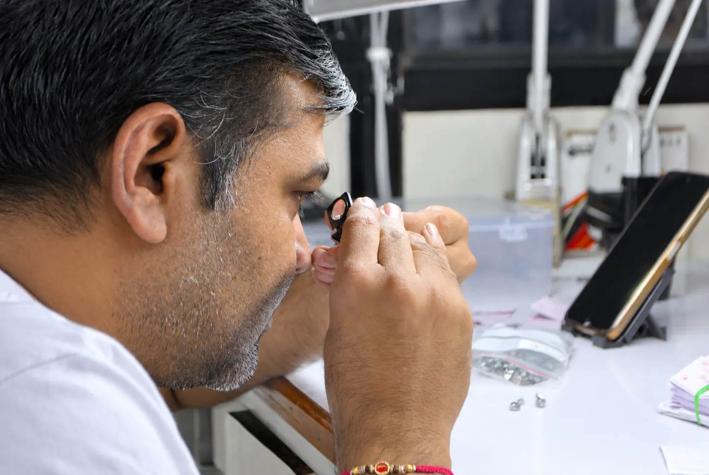 Sitaram craftsperson inspecting a stone through a loupe; exposure enhanced with AI